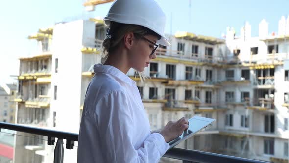 young engineer woman with helmet and tablet on building.