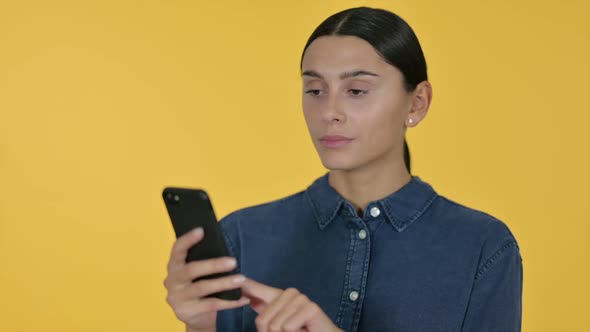 Latin Woman Using Smartphone Yellow Background alt