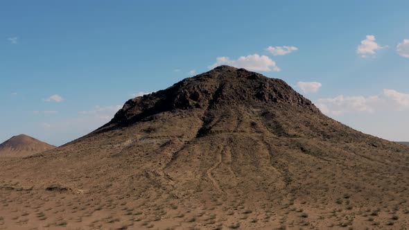 Fly over of rugged mountaintop revealing vast Mojave Desert, Aerial Dolly Zoom alt