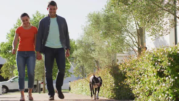 Happy caucasian couple is taking their dog for a walk alt