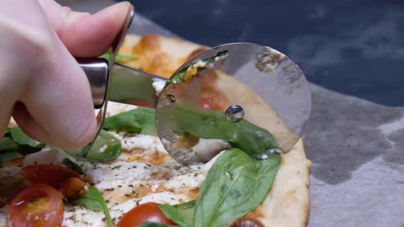 Close-up cutting pizza with a round cutter knife slow motion. camera movement