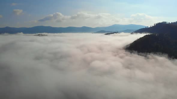 Aerial drone shot of amazing dense fog above river between mountains. alt