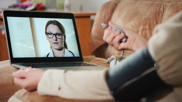 Elderly Woman Consults Doctor Via Webcam Measures Blood Pressure alt