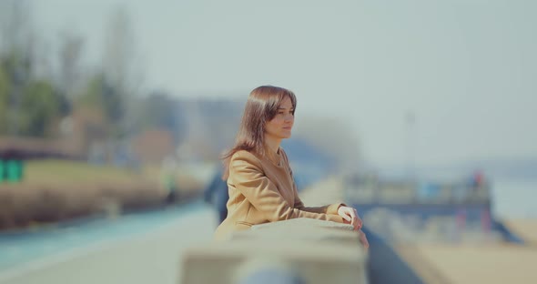 Young Business Lady is Standing at the Parapet on the Embankment and Dreaming alt