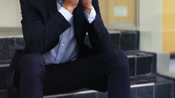 Depressed businessman sitting on stairs 4k alt