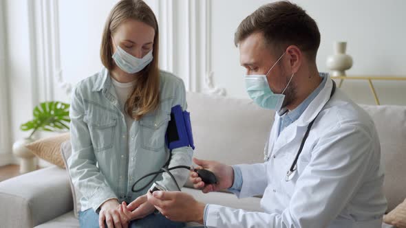 Doctor Measures a Woman's Blood Pressure While Sitting on the Couch alt