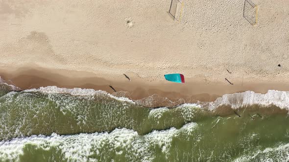 AERIAL: Top View Shot of People Walking on a Beach and Surfers Kite Waving in Wind