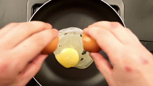 Human hands puts egg on the frying pan