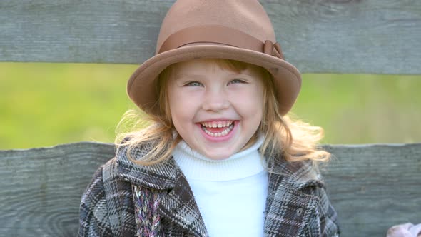 Funny little girl in a hat in an autumn park.