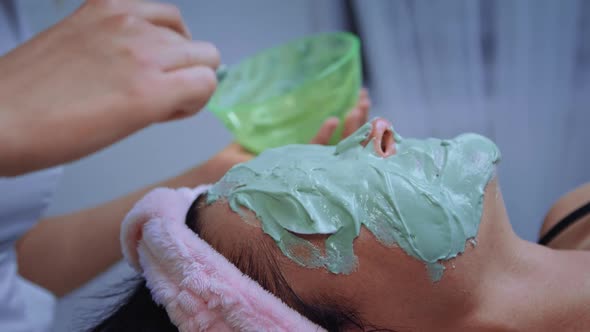 Cosmetologist Applies Alginate Mask with Spatula on Female Face alt