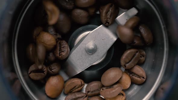 Fresh roasted coffee beans pouring in a grinder from glass jar. Top view. Slow motion