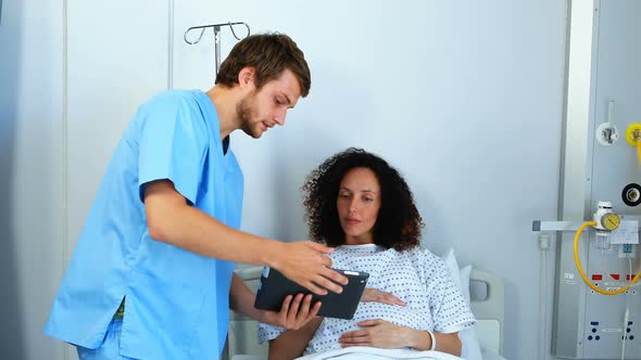 Doctor showing medical report to pregnant woman on digital tablet alt
