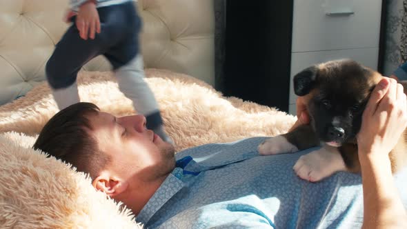 Man laying on sofa with puppy and children