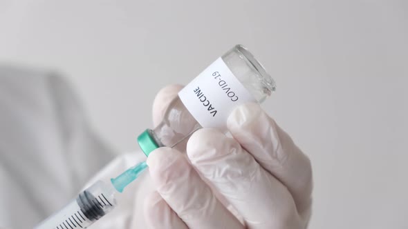 Doctor holding the covid-19 vaccine with his fingers. Vaccine and syringe in hand