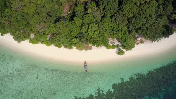 Aerial view of longtail boat at sandy beach in Thailand - camera pedestal up and backwards tracking alt