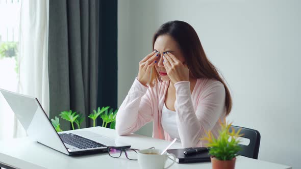 Tired and stressed young asian woman feel pain eyestrain and rubbing her eyes