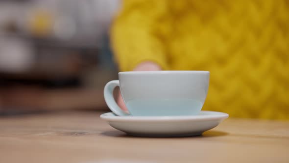 Female Hand Pushing Blue Coffee Cup at Cafeteria Counter alt