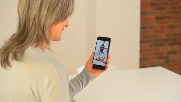 Mature Woman Talking Online From Home with a Doctor Having a Virtual Medical Checkup alt