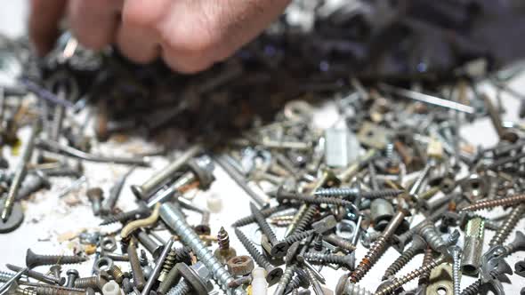 Hand Putting and Sorting Screws Nails Bolts and Washers on the Table alt