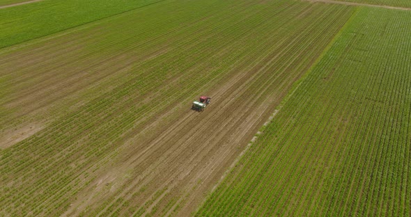 Fertilizer spreader in a large field, Aerial follow footage. alt