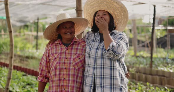 Happy Asian woman farmers looking to camera and laughing together on local organic vegetable farm. alt