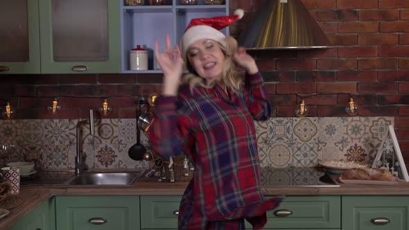 Happy Christmas Cheerful Woman Dancing at Home in Santa Claus Hat alt