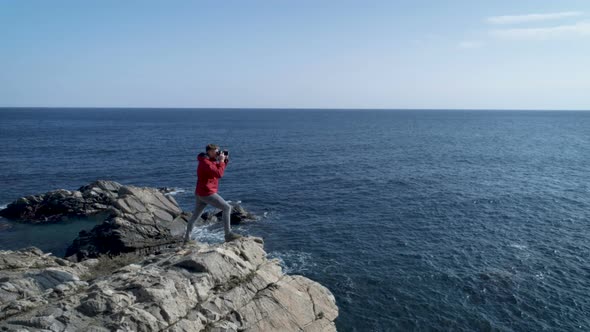Adventurer Taking Pictures Of The Sea While Standing On Cliff