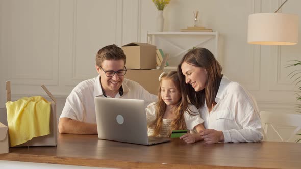 A Happy Family Uses a Laptop for Online Shopping, Sitting at Home. alt