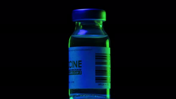 Vial of Vaccine for Coronavirus COVID19 Cure are Slowly Spinning Under Blue and Green Light alt