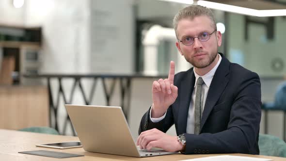Serious Businessman with Laptop Saying No with Finger Sign alt