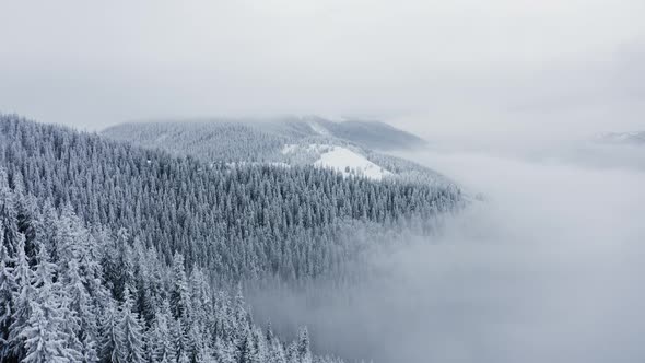Aerial Cinematic view of Stormy clouds above Winter Mountains, Flying above Frozen Fores alt