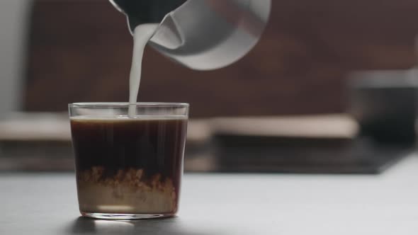 Slow Motion Pour Milk in Coffee in Tumbler Glass on Concrete Countertop with Copy Space alt