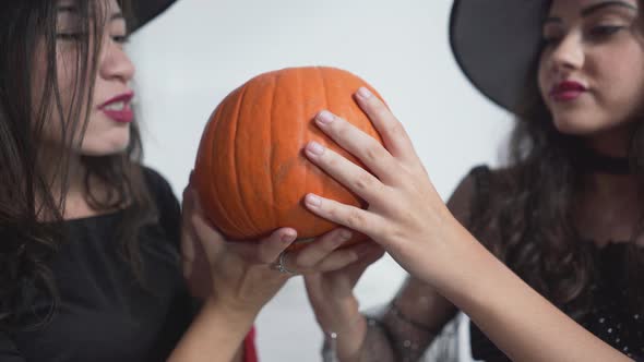 Young Girls In Witch Costume Holding And Rubbing Pumpkin During Halloween alt