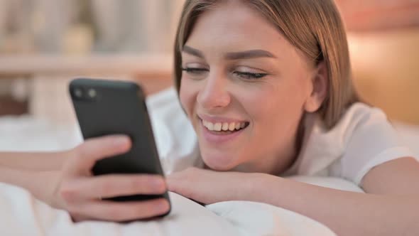 Close Up of Happy Young Woman Using Smartphone in Bed alt