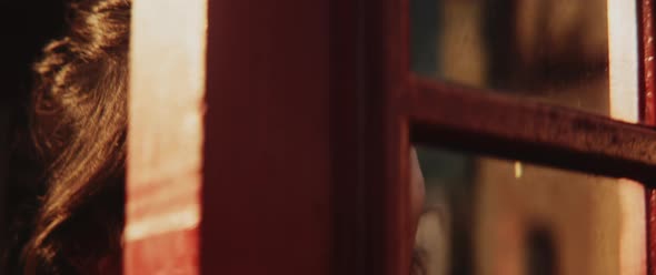 Happy smiley girl coming out of a red phone booth alt