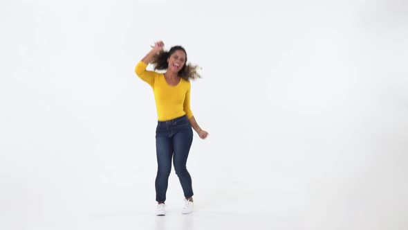 Happy young African American woman in casual yellow t-shirt dancing