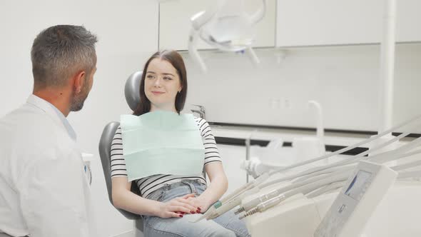 Lovely Young Woman Talking To Her Dentist at the Clinic