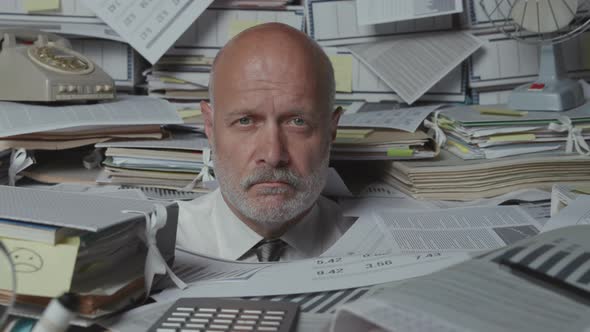 Sad stressed businessman under a lot of paperwork
