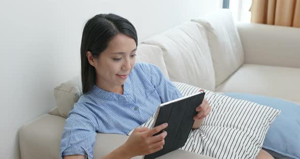 Woman look at tablet computer and sit on sofa at home