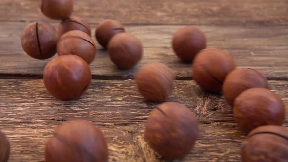 Macadamia nuts in shells fall on the old wooden vintage board alt