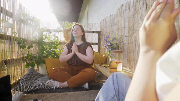 Woman Meditates with Friend Holding Crystals on Terrace