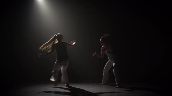 Capoeira in Darkness Under Spotlight at Studio on Black Background alt