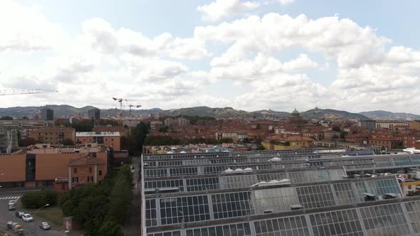 Building rooftop greenhouses with majestic view of Bologna city, aerial drone fly over view alt