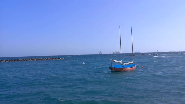Anchored boat with a kite surfer riding the waves in choppy water alt