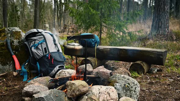 Backpack and Metal kettle on a campfire in the forest