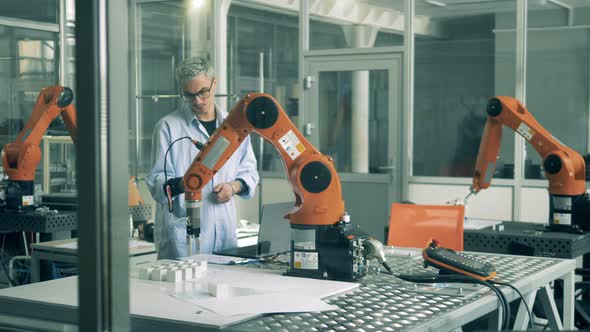 One Man Checks Working Robotic Arm on a Table. Modern Science Laboratory alt