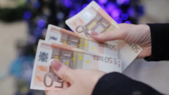 The Woman Believes Euro Banknotes on a Background of the Christmas Tree
