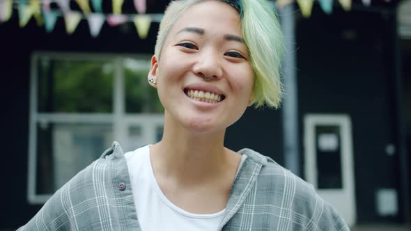 Close-up of Joyful Asian Lady with Cute Hairstyle Looking at Camera Smiling alt
