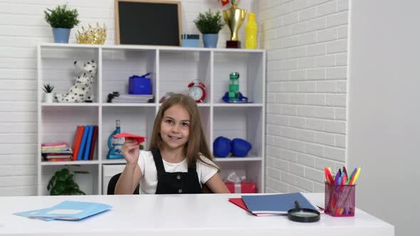 Happy Child Having Fun Playing with Paper Plane at School Lesson in Classroom School alt