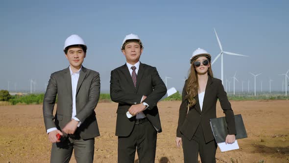 In the wind turbine field, businessman team is smiling proudly at the wind power project